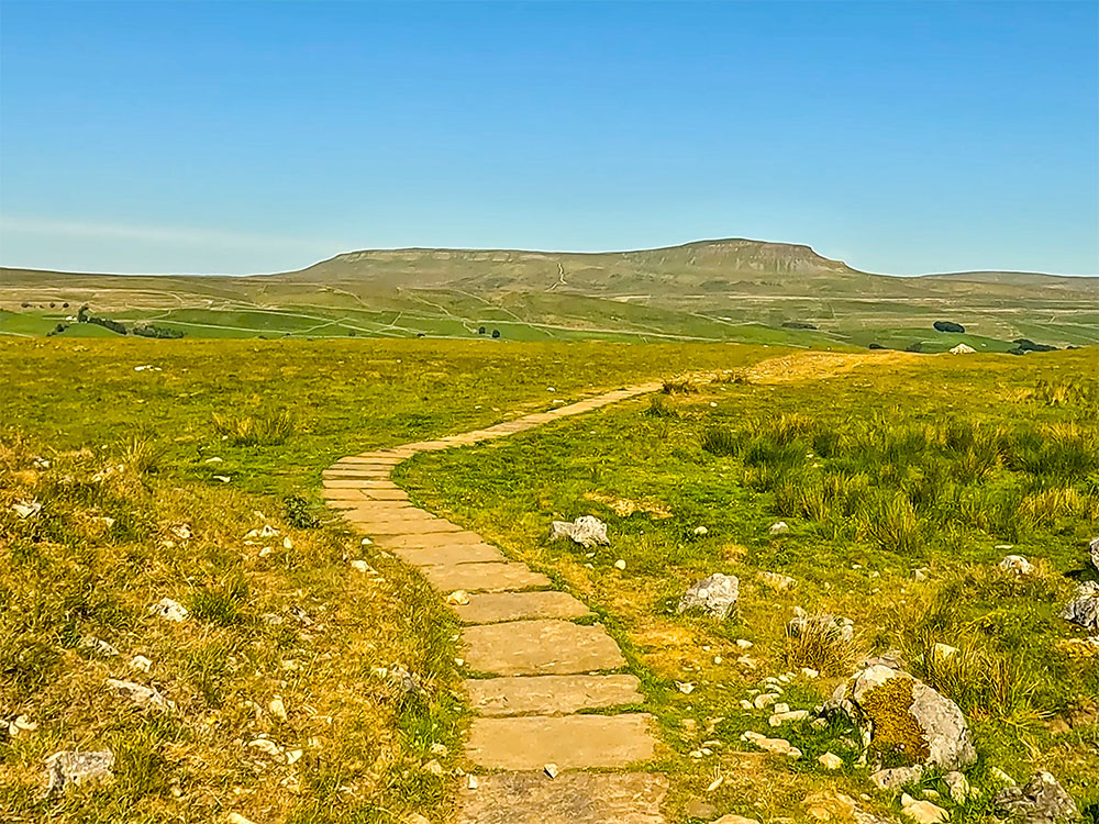 The flagged Yorkshire Three Peaks path as it heads back to Horton, with Pen-y-ghent on the horizon
