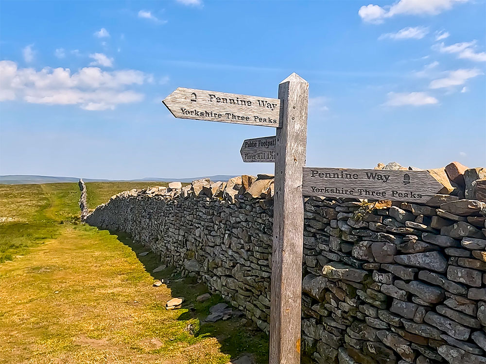The Pennine Way and Yorkshire Three Peaks signpost on the summit of Pen-y-ghent