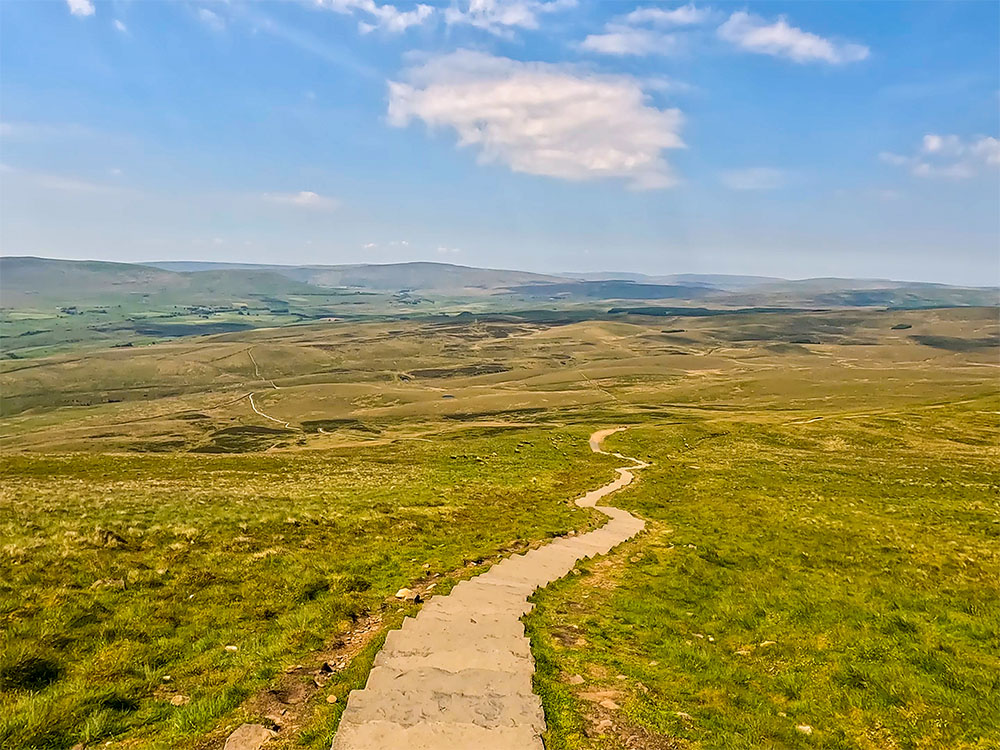 The Three Peaks path stretches out in front as you descend from Pen-y-ghent with Ingleborough and Whernside visible on the horizon