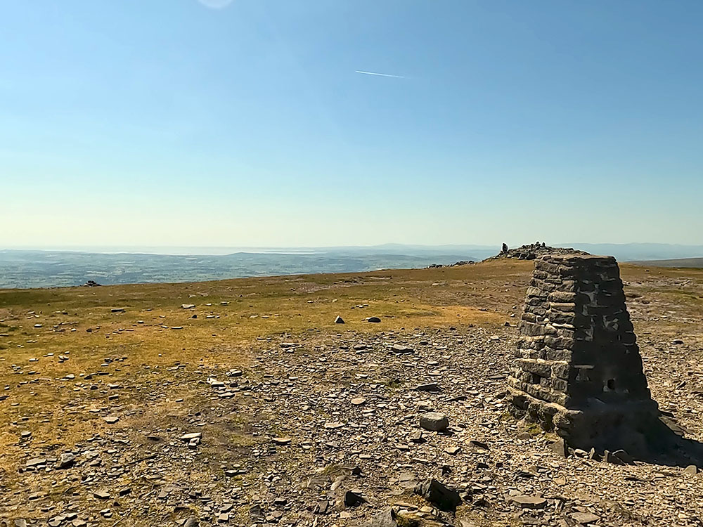 Looking out towards the sea at Morecombe Bay and the faint outline of the Lakeland Fells from Ingleborough's trig point