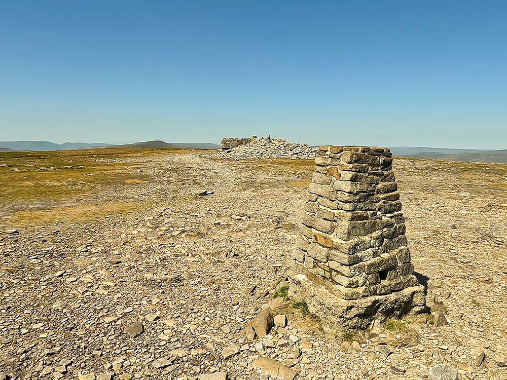 Looking towards the weather shelter, Whernside and the Howgills from Ingleborough's summit trig point
