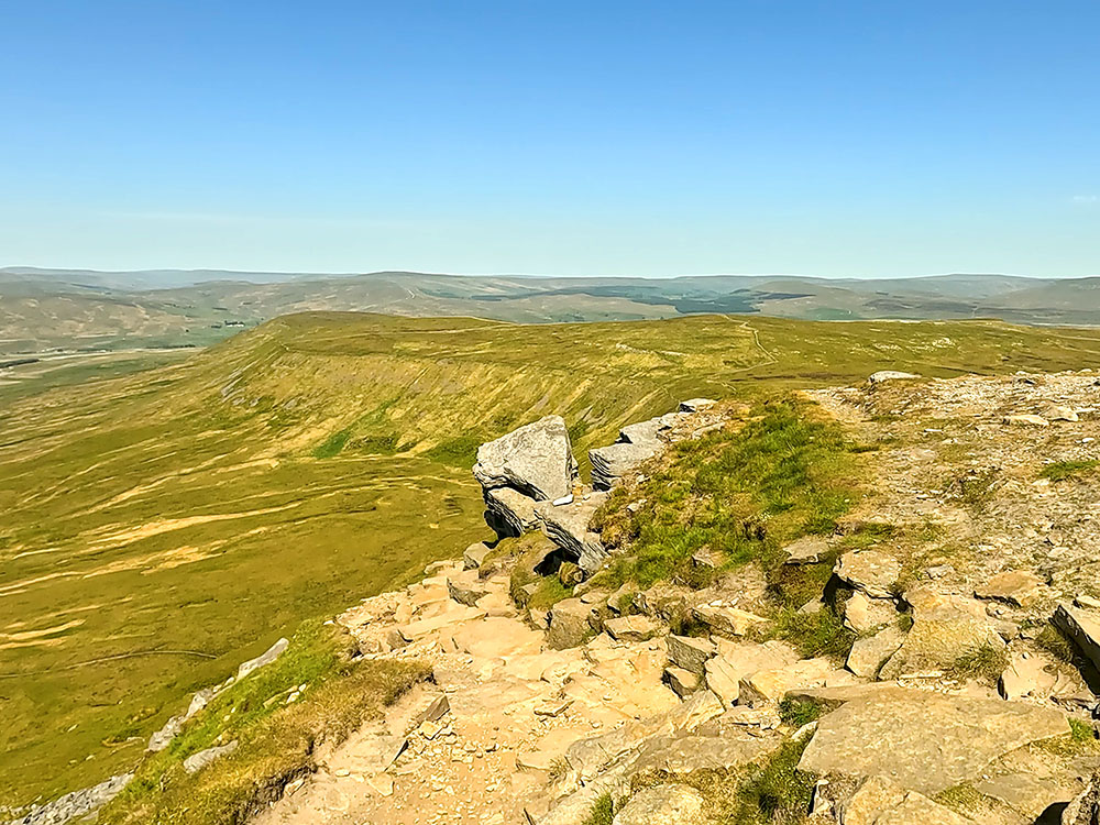 The path off Ingleborough's summit plateau passes by the left-hand side of the large boulder