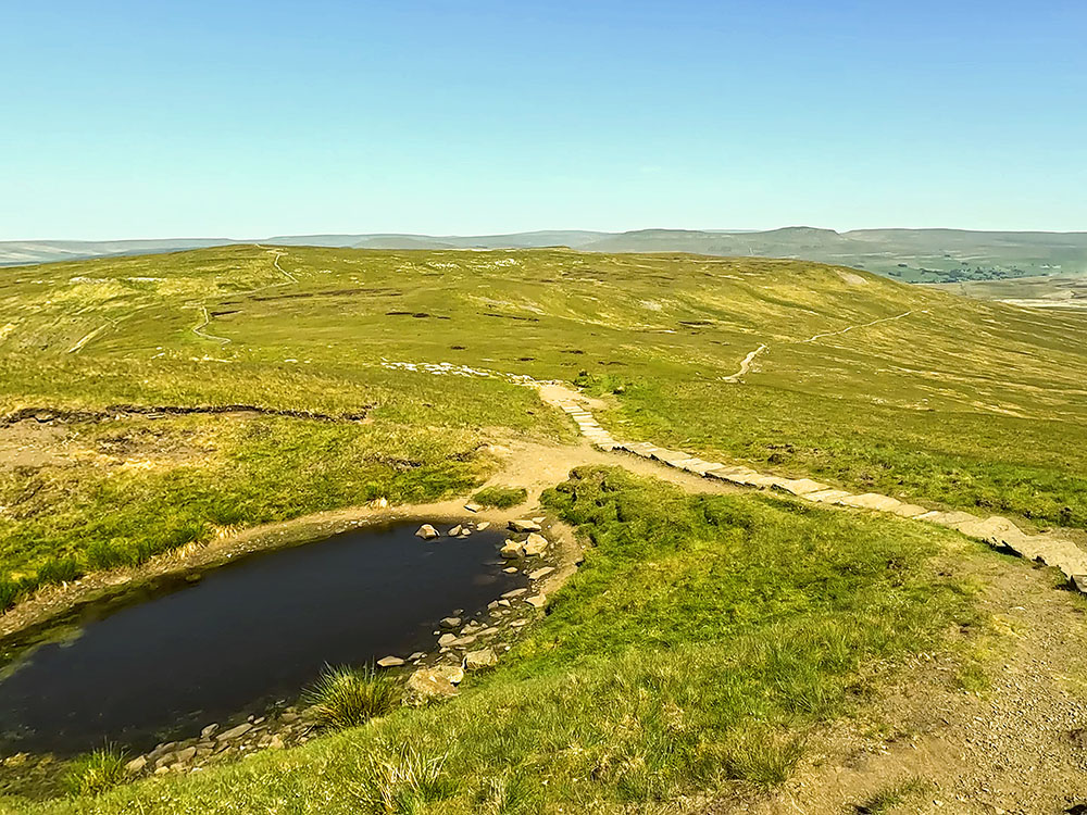 The path passes by the small tarn as it heads out across Simon Fell Breast