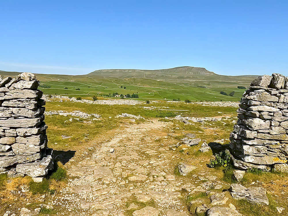 The path passes through the gap in the wall and then bends around to the right