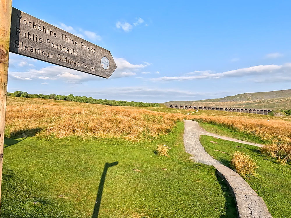Yorkshire Three Peaks footpath sign pointing towards the Ribblehead Viaduct