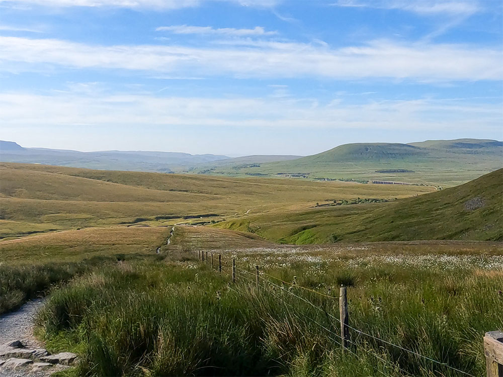 Looking back down the Dales High Way as it passes around Whernside towards Pen-y-ghent and Ingleborough